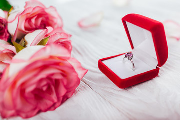 Silver ring with amethyst gem in red gift box and bouquet of roses. Proposal present for Valentines...