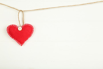Fabric heart hanging on white wooden background