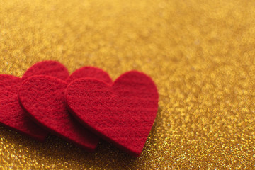 Obraz premium Red felt hearts on golden shiny background. Valentine's Day