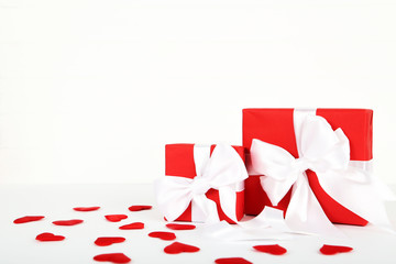 Gift boxes with ribbons and red hearts on white background