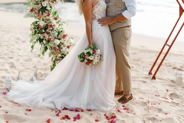 Close up male and female feet, newlyweds legs standing on the beach in water. Honeymoon, wedding couple on the beach