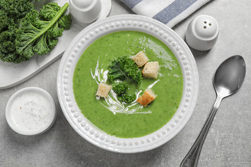 Tasty kale soup with croutons served on grey table, flat lay