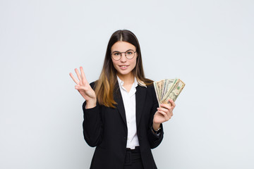 young pretty woman smiling and looking friendly, showing number three or third with hand forward,...