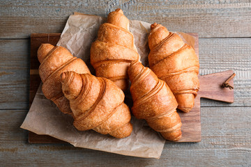 Tasty fresh croissants on wooden table, top view