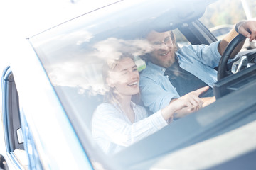 Transportation. Young couple traveling by electric car boyfriend driving while girlfriend pointing...