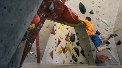 athletischer Mann springt beim Bouldern an Kletterwand totale Einstellung
