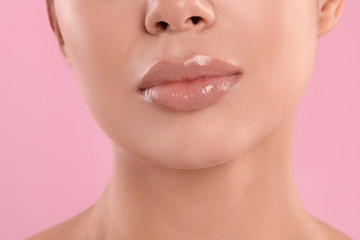 Young woman with beautiful full lips on pink background, closeup