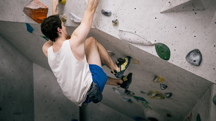 athletischer Mann beim Bouldern an Kletterwand