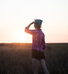 red-haired girl in spend time with pleasure in summer prairie at sunset