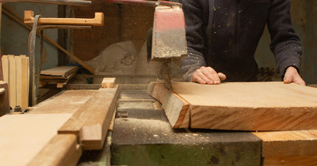 Young carpenter making wooden parts for the production of wooden furniture, joiner's shop work.