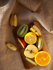 sliced fruits on a wooden board, on a forest towel