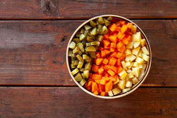 diced vegetables, carrots, potatoes, pickles. Top view on a wooden table.