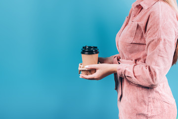 Woman hand holding a Coffee paper cup on blue background.