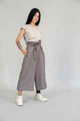 Freestyle. Diverse girl with leg prosthesis standing isolated on grey full body shot posing...