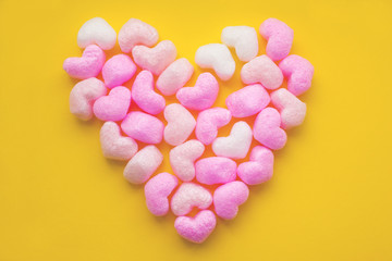 Delicious sweet corn colored sticks in the form of heart isolated on yellow background