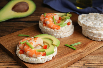 Puffed rice cakes with shrimps and avocado on wooden table