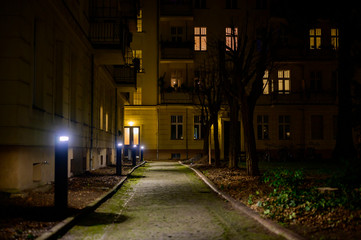 View of the rear building of a residential complex along an illuminated path at night in Berlin, Germany.