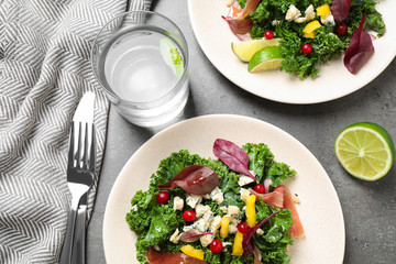 Tasty fresh kale salad on grey table, above view