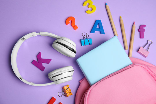 Flat lay composition with book and headphones on lilac background