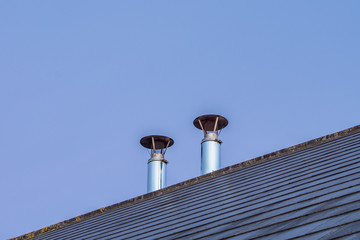 Two Chrome Chimneys on a Slated Roof at Dusk