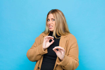 young blonde woman feeling disgusted and nauseous, backing away from something nasty, smelly or...