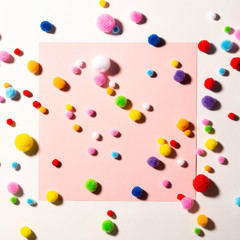 Holiday background with colorful soft fluffy balls for holiday decor, pink paper background