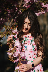 Fototapeta premium Close up of beautiful woman near the pink tree with makeup close her eyes