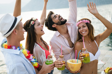 Group of friends having fun at summer party and drinking cocktail
