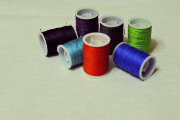 Linen, textiles, threads, needles, pins. Sewing supplies on a white table.
