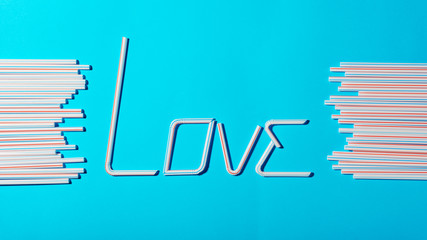 The word "love" from plastic cocktail straws on a blue background, an alternative concept for the Valentine's day background