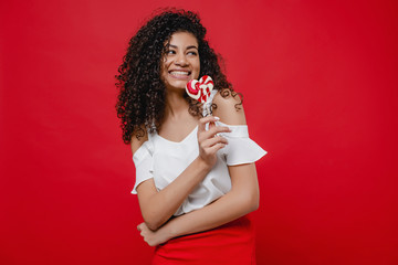 beautiful black woman with heart shaped lollypop candy on red background
