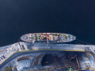 Loading coal mining in port on cargo tanker ship with crane bucket of train. Aerial top view