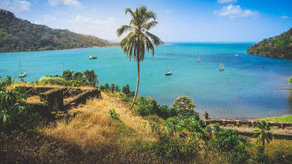 Fototapeta na wymiar A beautiful panoramic view of the Pirate Bay of Portobelo in Panama with its historical Forts Ruins & Cannons on a Hill with some Sailboats anchored in the Blue Lagoon at the Caribbean Coast.