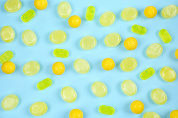 Delicious lemon candies on light blue background, flat lay