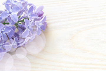 Fototapeta na wymiar Beautiful floral blank for design - a border of lilac flowers on a wooden table with copy space for text