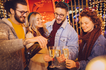 Group of happy friends drinking champagne and celebrating New Year at the street. New year party.