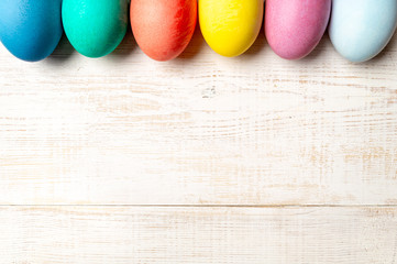 Easter concept. Colorful eggs on white wooden background with copy space for text. Top down view or flat lay