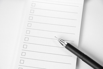 Blank to do list planner with checklist and black pen on white background, close up