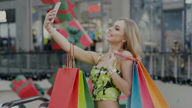 girl doing piture of herself smiling with shopping bags