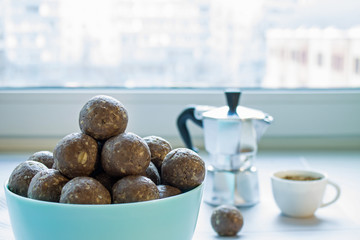 Healthy energy balls of chocolate and oatmeal in a porcelain Cup and coffee pot on the background of the window