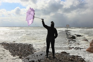 woman with pink umbrella fighting against  the strong sea wind , storm forecast