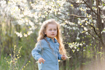 Little blonde girl having fun in the spring park.