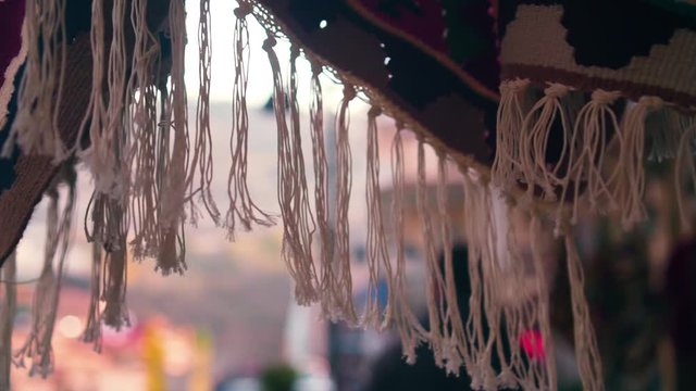 Close-up of a white fringed antique rug in an oriental style on a market in the background of people passing by.