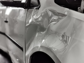 A small dent in the fender of a white metallic European car
