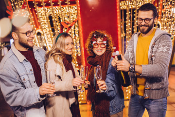 Group of happy friends drinking champagne and celebrating New Year at the street. New year party.