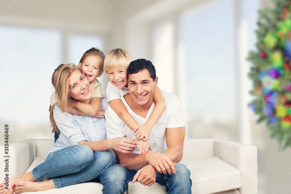 Wall mural beautiful smiling family sitting at sofa at home