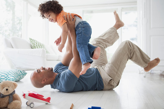 Father lying on the floor and lifting toddler son