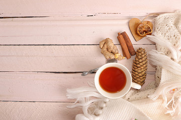 Fototapeta na wymiar Winter composition. Hygge style concept. Cozy female home table with knitted blanket, cup of tea, cinnamon, old wooden pink background. Flat lay, top view, copy space.