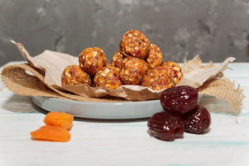 Homemade energy balls like a healthy breakfast or a snack of raisins, dried apricots, dates, nuts and oatmeal. Energy balls lie on crumpled paper on a gray ceramic plate on a gray background. 