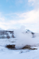 An erupting soaring geyser in the Valley of Geysers. Magnificent Iceland in the winter.